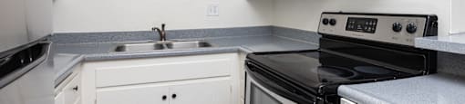 an empty kitchen with white cabinets and black appliances
