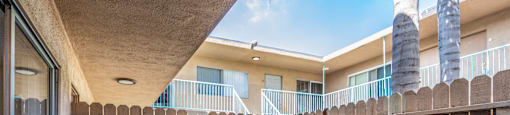 an empty patio with a wooden fence in front of an apartment building