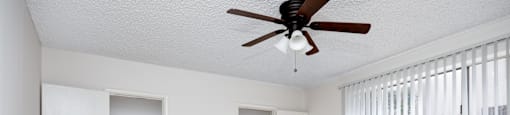 an empty living room with a ceiling fan and two closets
