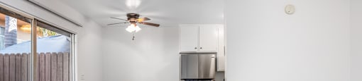an empty living room with a ceiling fan and a sliding glass door