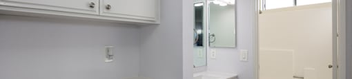 a white bathroom with white cabinets and a white toilet and sink
