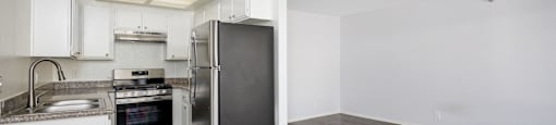 an empty kitchen with white cabinets and a stainless steel refrigerator