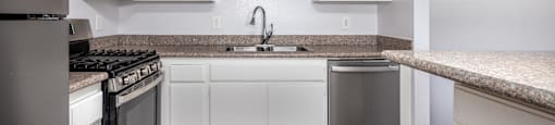 A kitchen with white cabinets and a granite countertop.