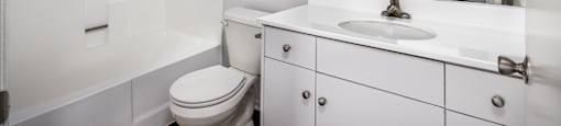 A white bathroom with a toilet, sink, and mirror.