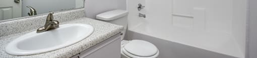 A white bathroom with a sink, toilet, and bathtub.