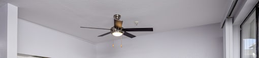 A room with a ceiling fan and wooden flooring.