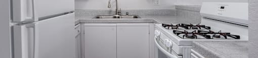 A white kitchen with a refrigerator, stove, and cabinets.
