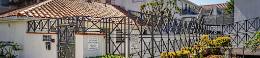 A white house with a black gate and a brown roof.