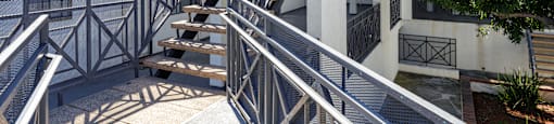 A staircase with a metal railing leads up to a white building.