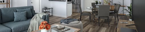 A modern living room with a grey sofa, a glass coffee table, and a television.