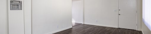 an empty living room with white walls and wood flooring
