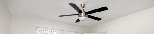 an empty living room with a ceiling fan and a window