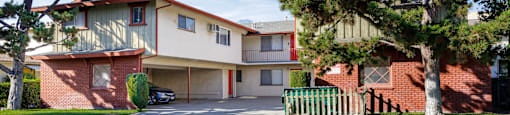 a street view of an apartment building with a white fence