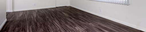 an empty living room with wood flooring and a window