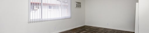an empty living room with a window and wood flooring
