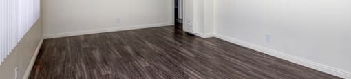 an empty living room with wood flooring and white walls