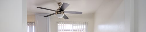 an empty kitchen with a ceiling fan and a window