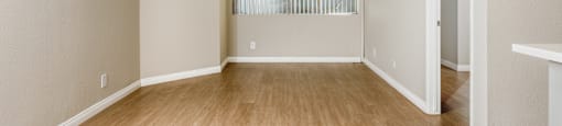 A room with wooden flooring and a window with blinds.