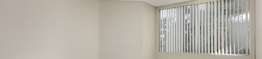 Empty room with wooden floor and a window with blinds.