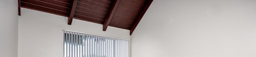 Empty room with wooden floor and a window with blinds.