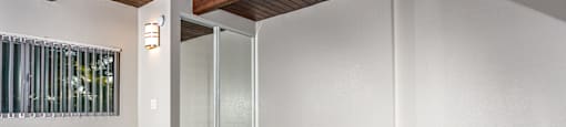 A room with a wooden ceiling and a glass door.