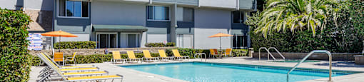 a swimming pool with chairs in front of a building