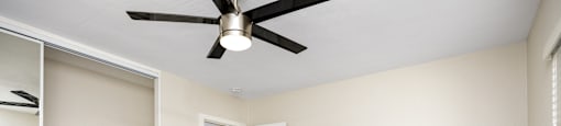 an empty living room with a ceiling fan and a closet