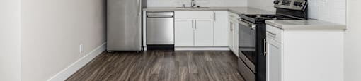an empty kitchen with white cabinets and stainless steel appliances