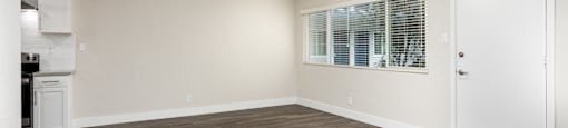 an empty living room with a ceiling fan and a kitchen
