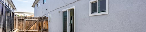 the outside of a white house with a patio and a wooden fence