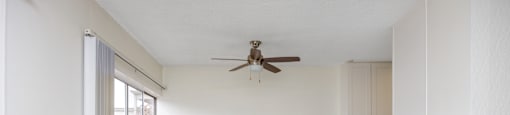 an empty living room with white walls and a ceiling fan
