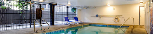 a swimming pool with chairs and a fence around it