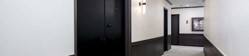 a hallway with black doors and white walls and a carpeted floor