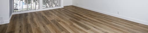 a living room with white walls and wood flooring and a window