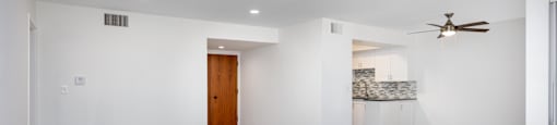a living room and kitchen with white walls and wood floors