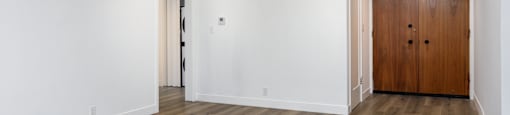 a living room with white walls and a wooden door