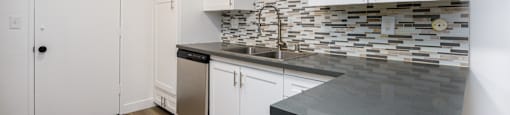 a kitchen with white cabinets and a counter top and a sink
