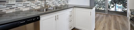 a kitchen with white cabinets and a sink and a window