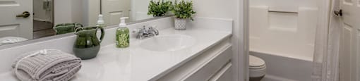 A white bathroom with a mirror, sink, and toilet.