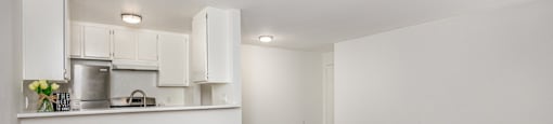 A kitchen with white cabinets and a wooden floor.