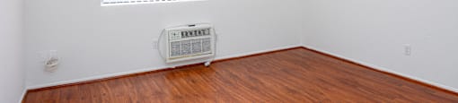 an empty room with a wood floor and an air conditioner