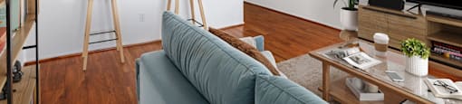 A living room with a blue couch and a wooden floor.