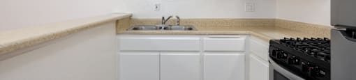 a kitchen with white cabinets and a sink and a stove