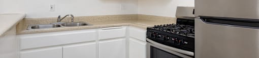 an empty kitchen with white cabinets and stainless steel appliances