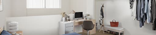 A bedroom with a bed, desk, chair, and closet.