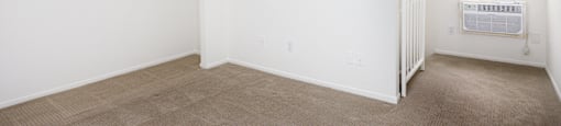 an empty room with a radiator and a window in a home with white walls