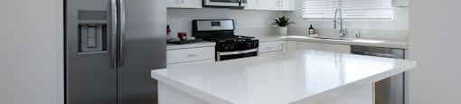 a white kitchen with stainless steel appliances and a large island