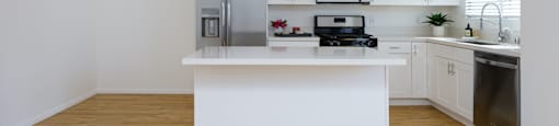 a white kitchen with a large island and stainless steel appliances