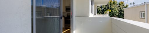 a balcony with a glass door and a white wall
