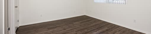 A room with wooden flooring and a window with blinds.